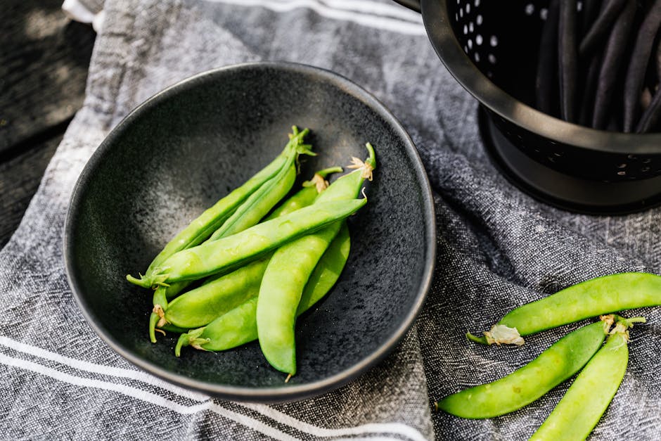 Petits pois frais en cosses présentés dans un bol en bois